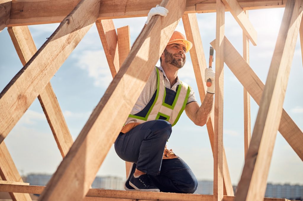 joyous construction site worker with hammer building a roof carcass 1024x682 1